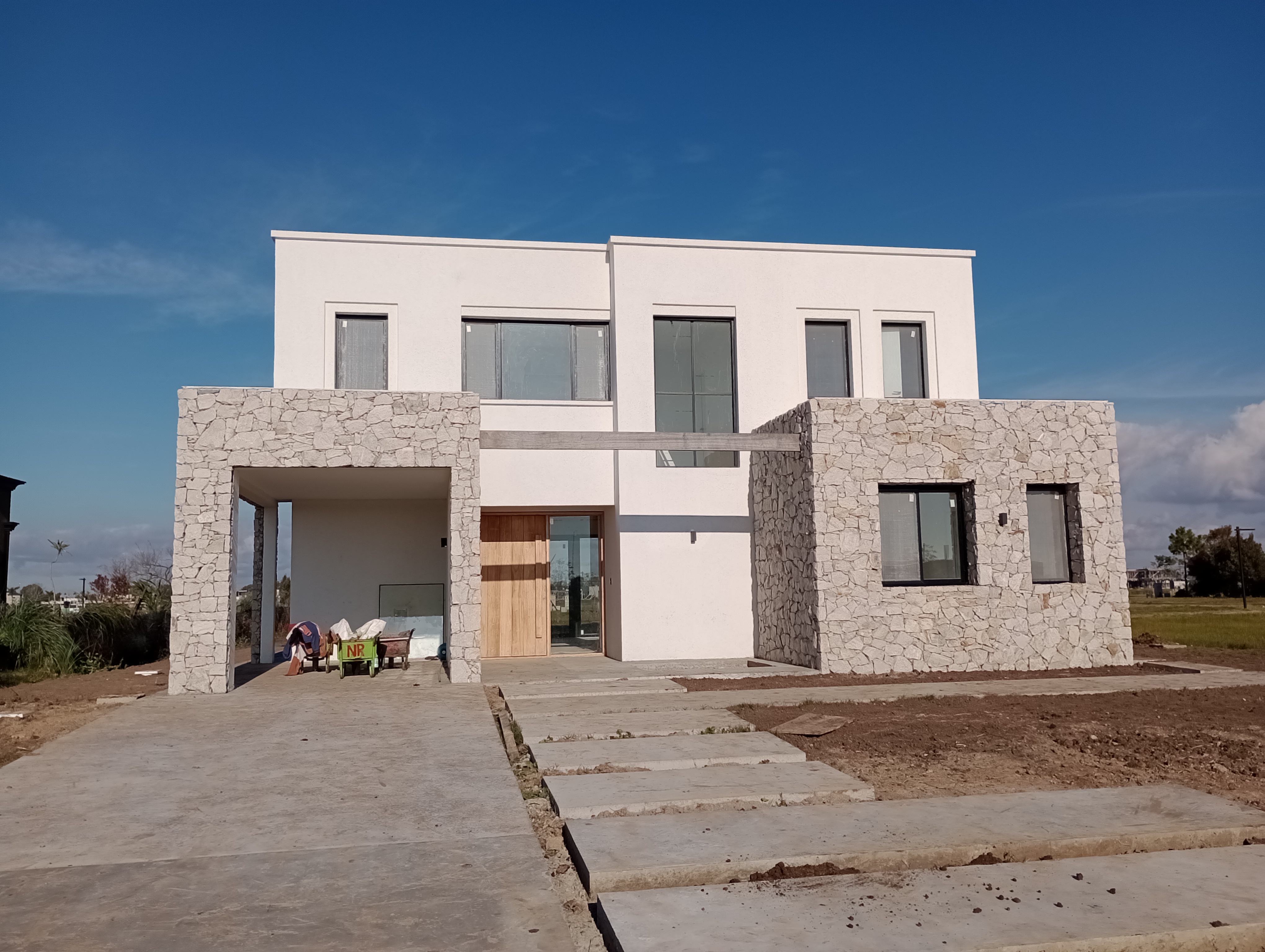 Vivienda unifamiliar en barrio cerrado, fachada blanca con piedra natural, GBA