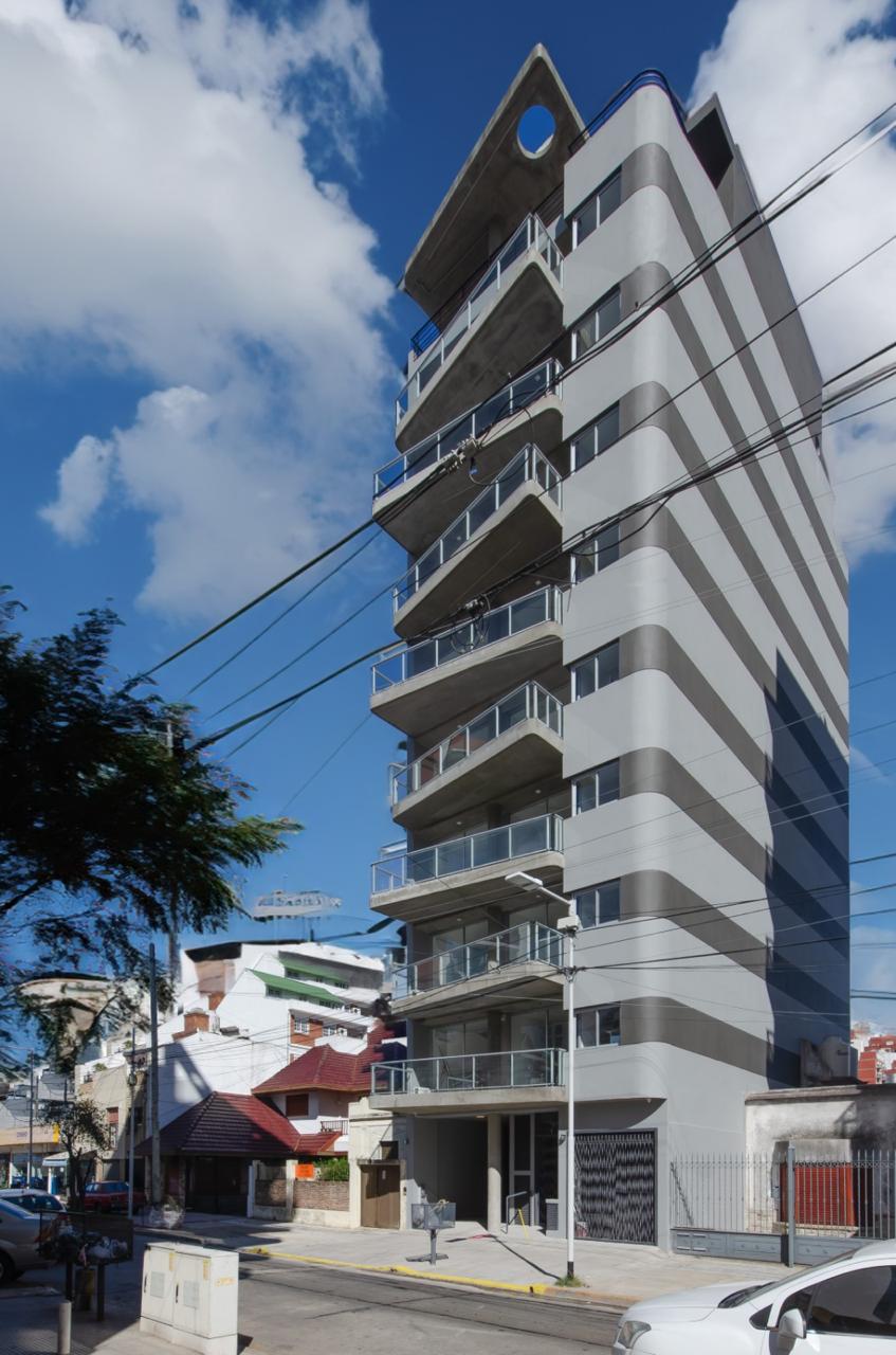 Edificio residencial terminado, fachada oscura, cielo azul, GBA