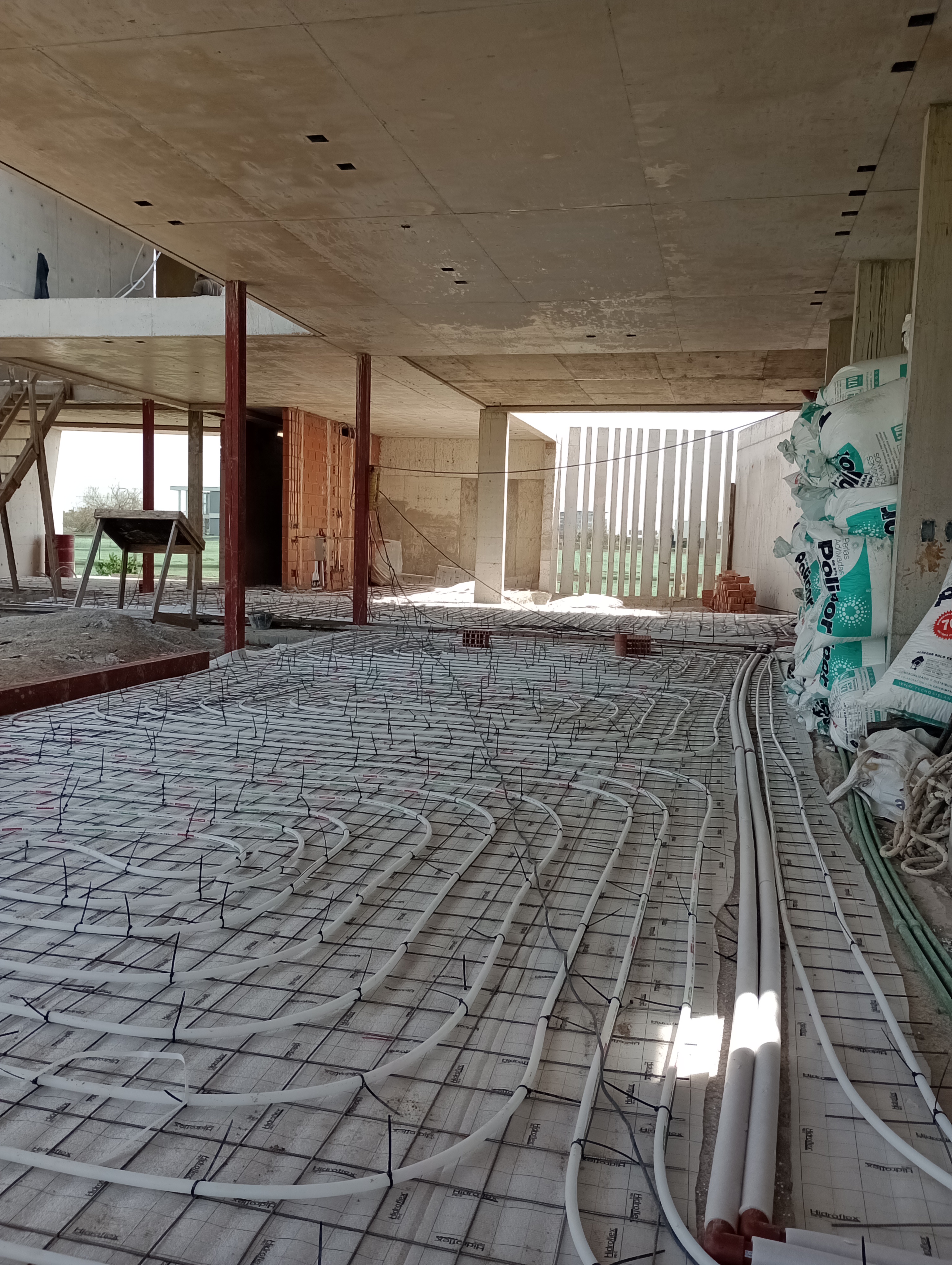 Instalación de piso radiante en perspectiva, operarios al fondo, GBA